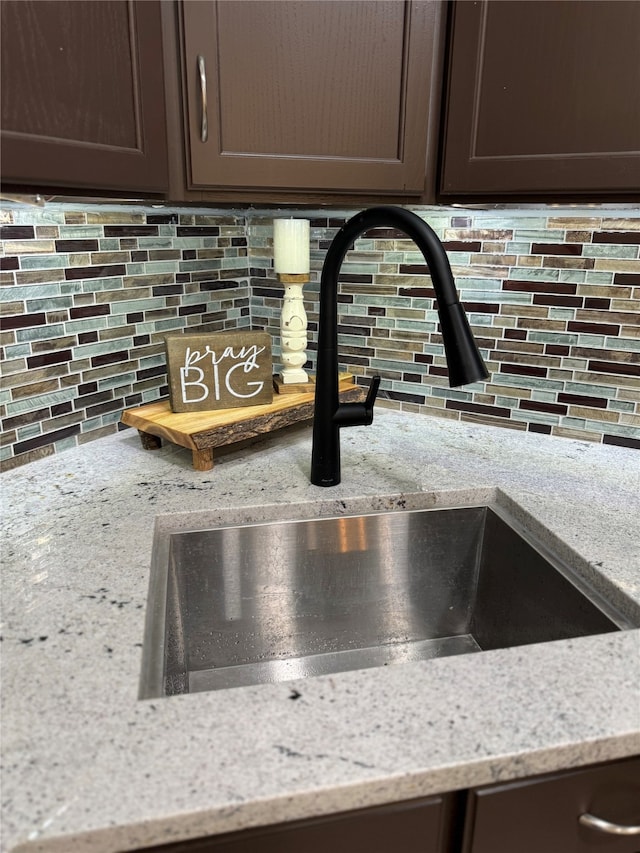 interior details with light stone countertops, backsplash, and sink