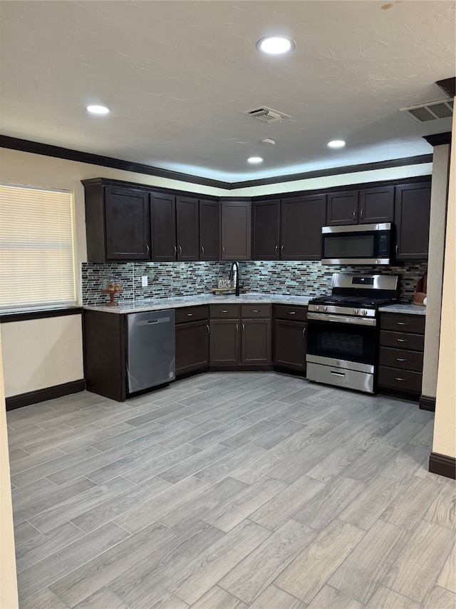 kitchen with light wood-type flooring, sink, appliances with stainless steel finishes, and ornamental molding