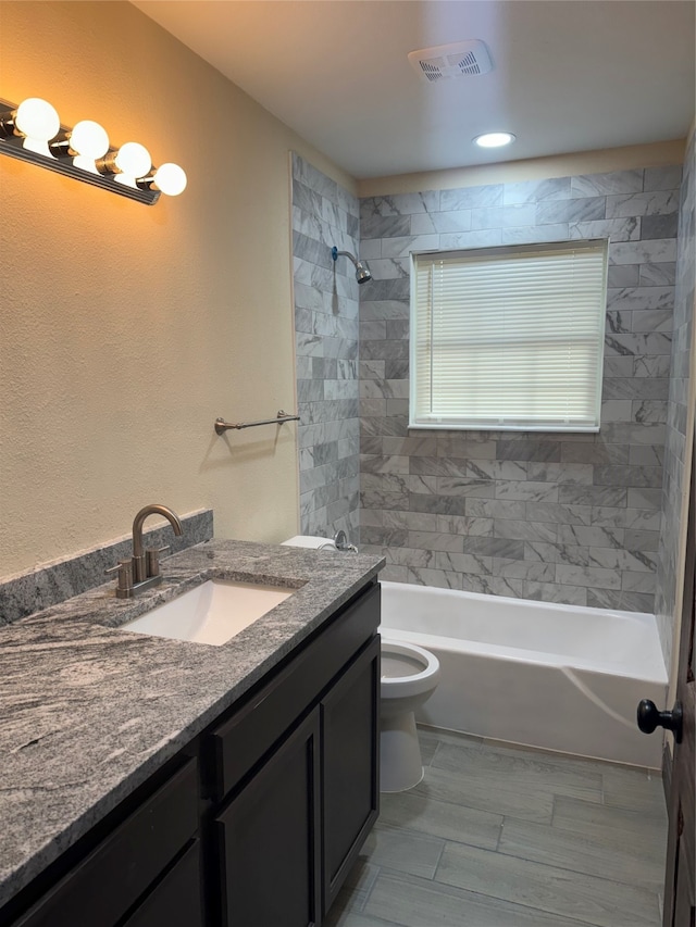 full bathroom featuring vanity, toilet, and tiled shower / bath combo