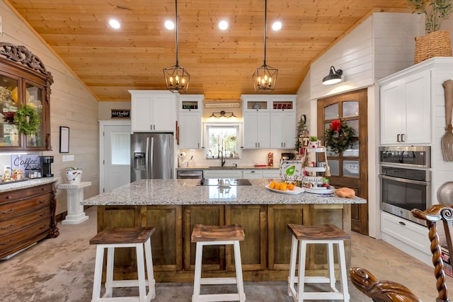 kitchen with light stone counters, wood walls, a kitchen island, appliances with stainless steel finishes, and a breakfast bar area