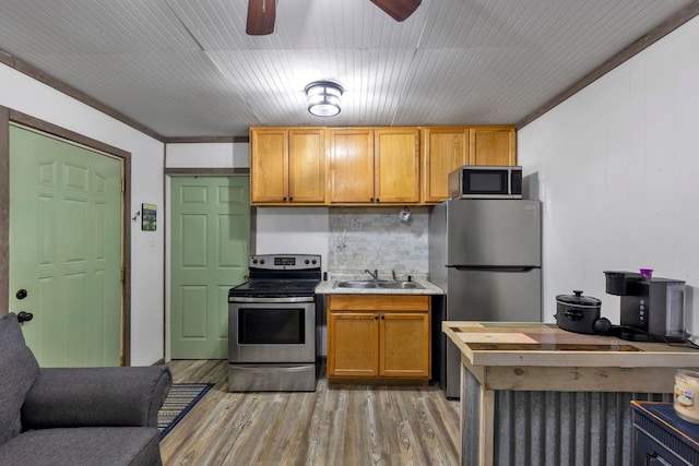 kitchen featuring appliances with stainless steel finishes, crown molding, sink, and light hardwood / wood-style floors