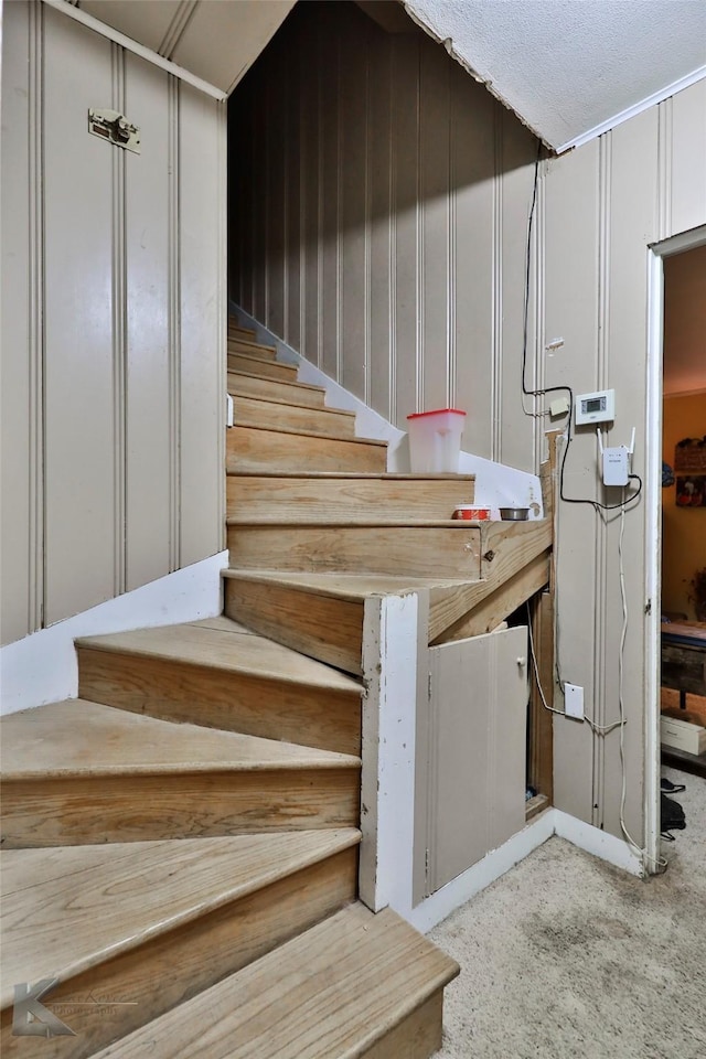 staircase featuring a decorative wall and carpet