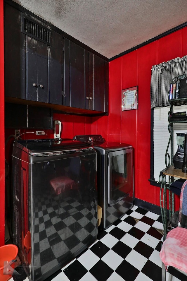 clothes washing area featuring tile patterned floors, washer and dryer, cabinet space, and a textured ceiling