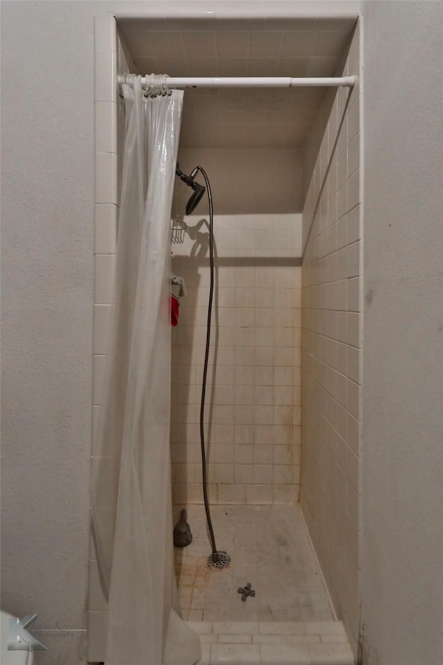 bathroom featuring a shower stall and a textured wall