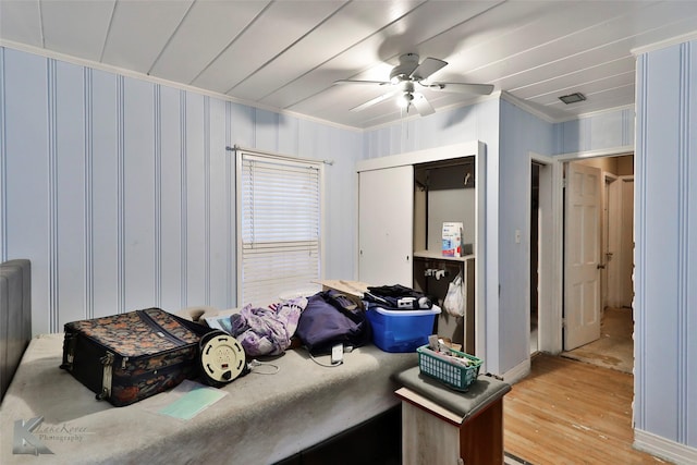 bedroom with ceiling fan, crown molding, a closet, and light wood-style flooring
