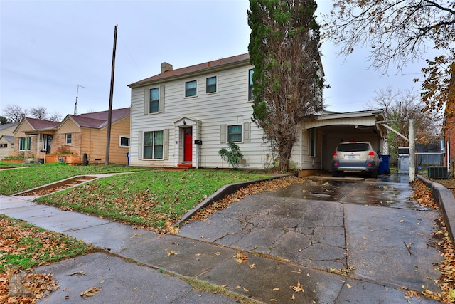 colonial-style house with a front lawn, central AC unit, and a carport