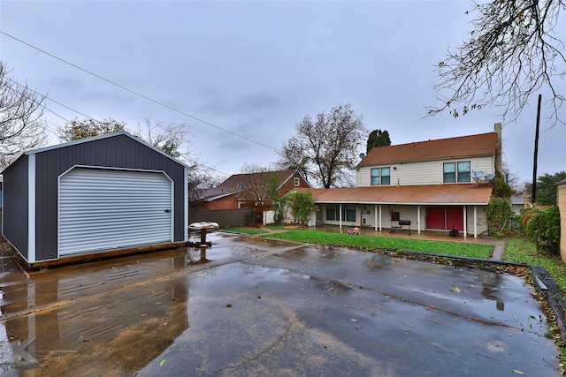 view of front of house featuring fence, a porch, an outbuilding, and driveway