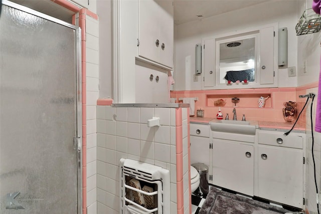 full bath with tile walls, wainscoting, a stall shower, and vanity