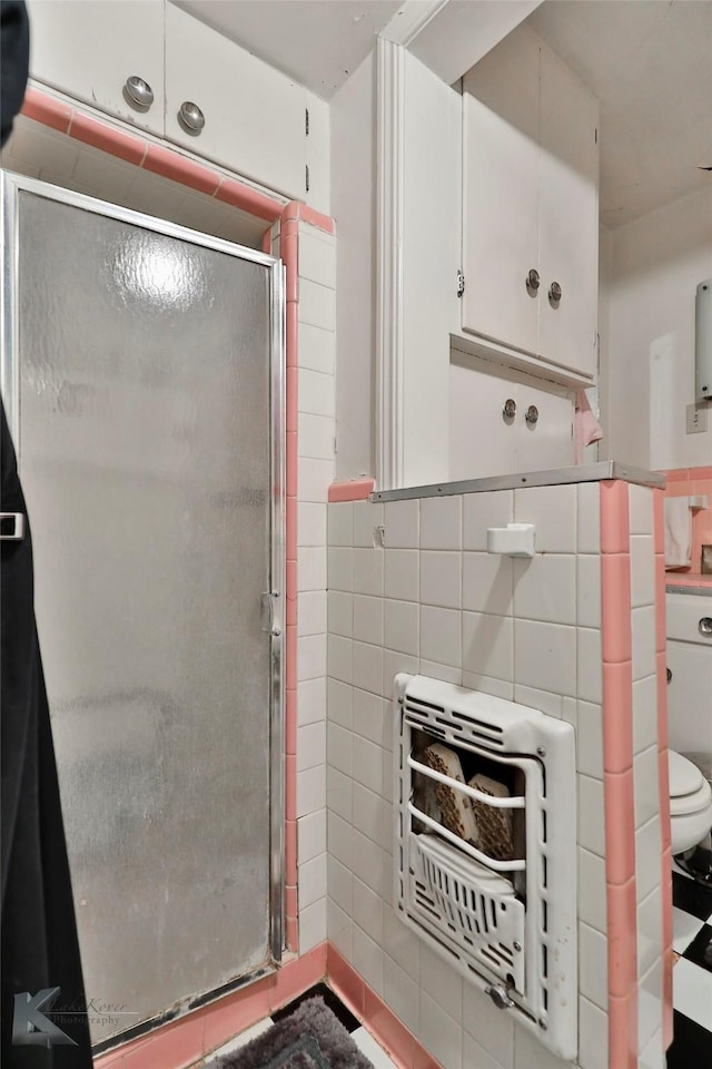 bathroom with a wainscoted wall, tile walls, and a shower stall