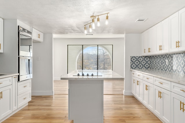 kitchen featuring stainless steel double oven, white cabinetry, and light hardwood / wood-style flooring