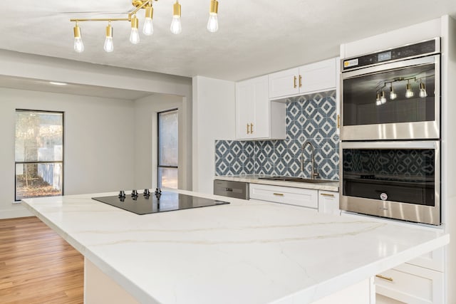 kitchen featuring white cabinetry, sink, stainless steel appliances, light hardwood / wood-style flooring, and backsplash