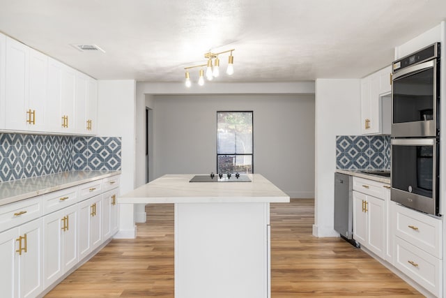 kitchen featuring backsplash, a kitchen island, appliances with stainless steel finishes, light hardwood / wood-style floors, and white cabinetry