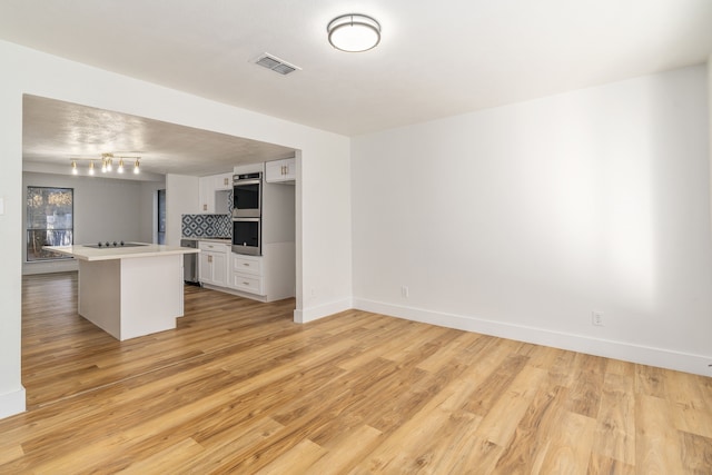 kitchen featuring backsplash, white cabinets, light hardwood / wood-style floors, and a kitchen island