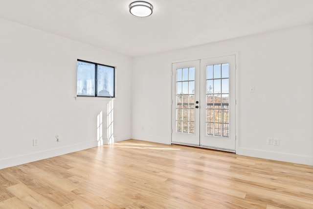 empty room featuring plenty of natural light, light wood-type flooring, and french doors