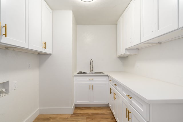 laundry room with washer hookup, sink, cabinets, and light hardwood / wood-style flooring