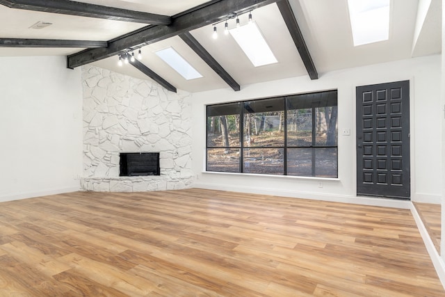 unfurnished living room with lofted ceiling with beams, a fireplace, and light hardwood / wood-style floors