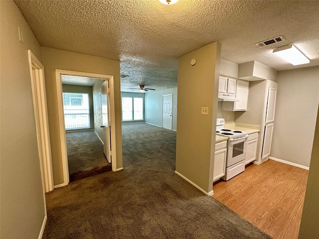 kitchen with white cabinetry, electric range, ceiling fan, a textured ceiling, and light carpet