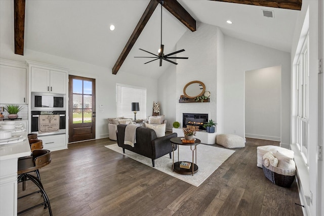 living room featuring high vaulted ceiling, a large fireplace, dark hardwood / wood-style flooring, ceiling fan, and beam ceiling