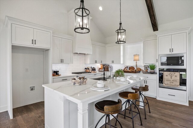 kitchen featuring hanging light fixtures, stainless steel appliances, an island with sink, and white cabinets