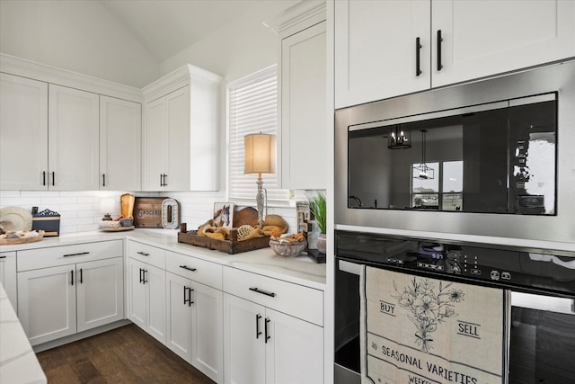 kitchen with built in microwave, white cabinetry, vaulted ceiling, dark hardwood / wood-style floors, and backsplash