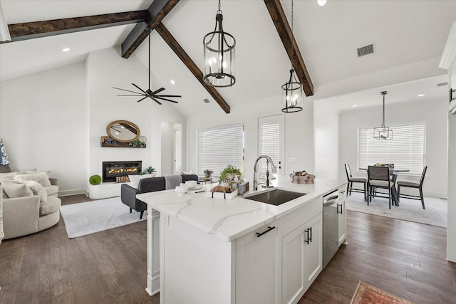 kitchen featuring sink, light stone counters, stainless steel dishwasher, pendant lighting, and a kitchen island with sink