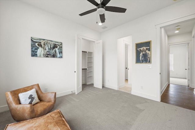 living area with ceiling fan and carpet flooring