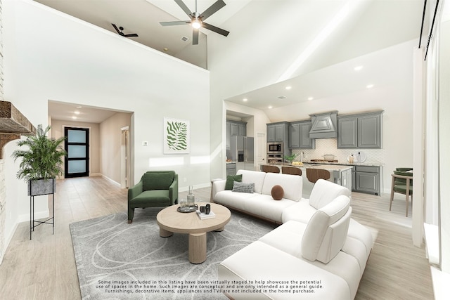 living room with light hardwood / wood-style flooring, ceiling fan, and high vaulted ceiling