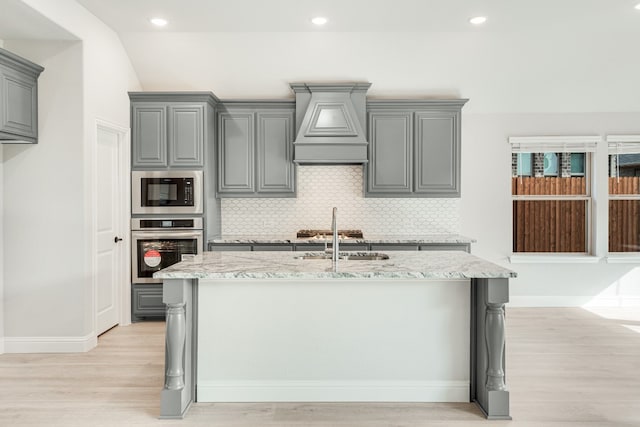 kitchen featuring black microwave, custom exhaust hood, light hardwood / wood-style floors, stainless steel oven, and gray cabinets