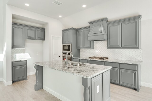 kitchen featuring gray cabinetry, tasteful backsplash, custom range hood, and light wood-type flooring