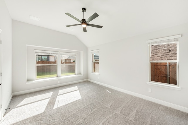 empty room with lofted ceiling, ceiling fan, and light colored carpet