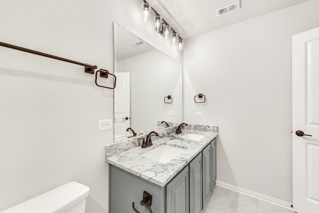 bathroom featuring toilet, dual sinks, tile floors, and large vanity