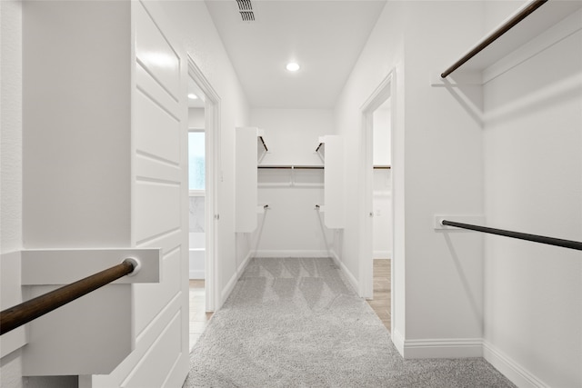 walk in closet featuring light colored carpet