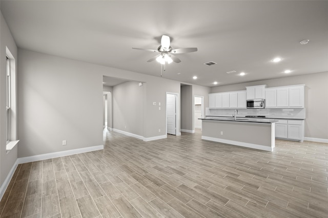 unfurnished living room featuring sink, ceiling fan, and light hardwood / wood-style floors