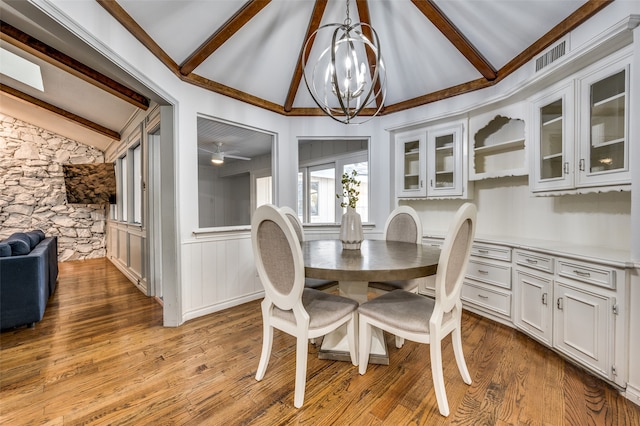 dining room with hardwood / wood-style flooring, lofted ceiling with beams, and ceiling fan with notable chandelier