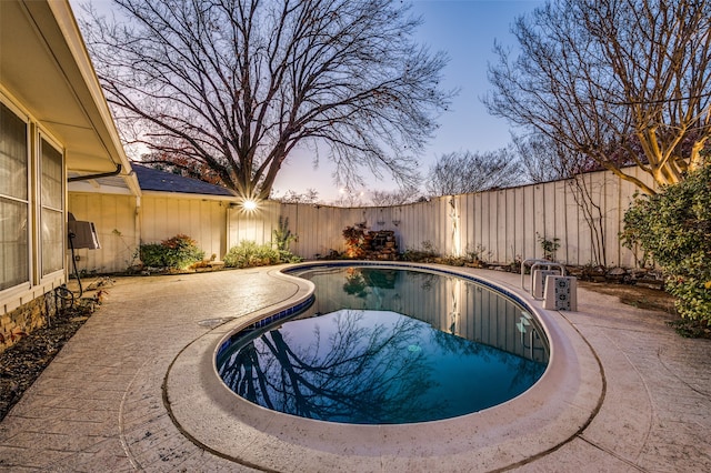 pool at dusk with a patio area