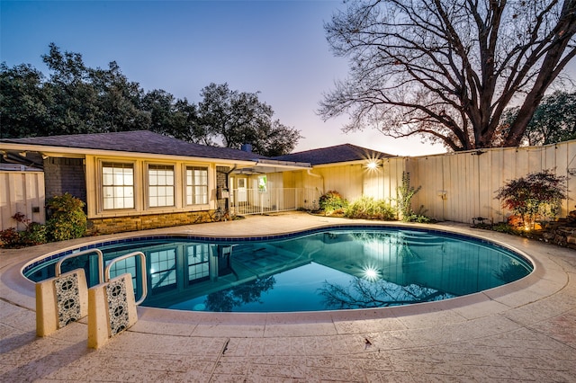 pool at dusk with a patio area