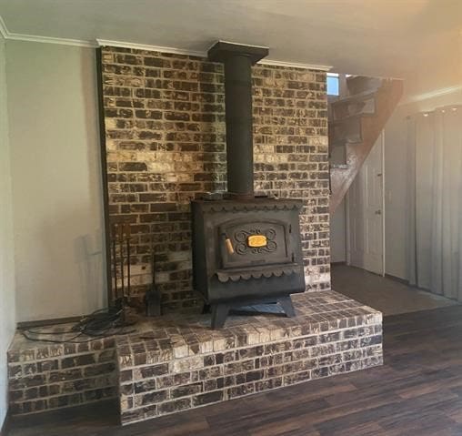 details featuring a wood stove, ornamental molding, and wood-type flooring