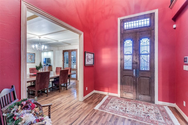 foyer featuring french doors, coffered ceiling, beamed ceiling, a notable chandelier, and wood-type flooring