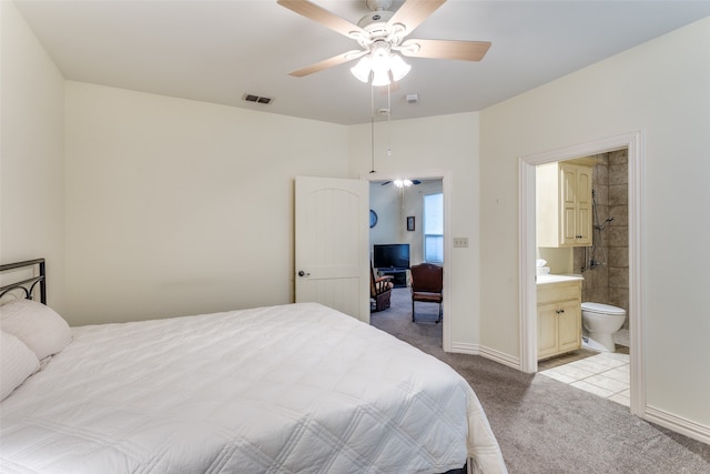 bedroom featuring ceiling fan, light colored carpet, and connected bathroom