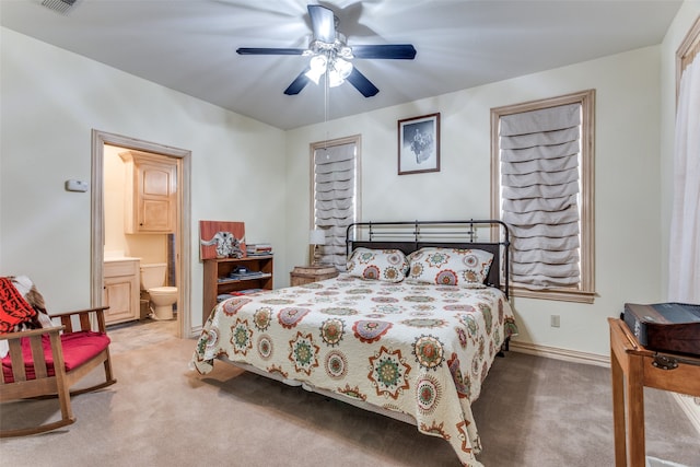 carpeted bedroom with ensuite bath and ceiling fan