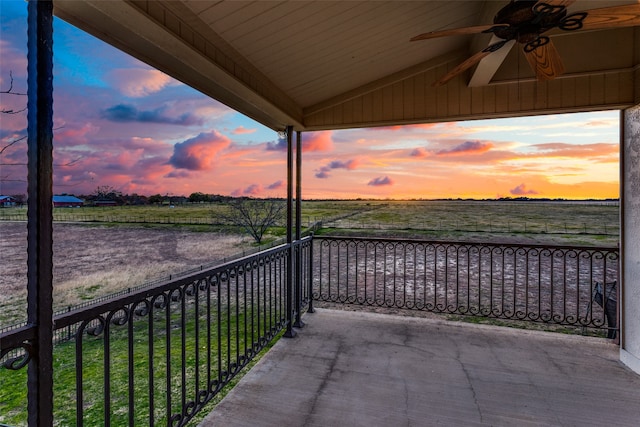 balcony at dusk featuring ceiling fan and a rural view