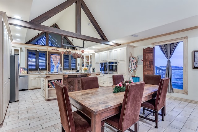 dining room with sink, beamed ceiling, and high vaulted ceiling