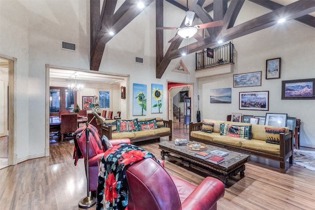 living room with hardwood / wood-style floors, high vaulted ceiling, and ceiling fan with notable chandelier