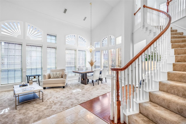 tiled living area with high vaulted ceiling, a wealth of natural light, visible vents, and stairs