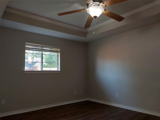 empty room featuring ceiling fan, dark hardwood / wood-style flooring, a tray ceiling, and ornamental molding