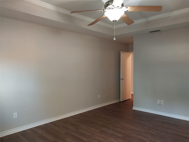 empty room with dark wood-type flooring, ornamental molding, a tray ceiling, and ceiling fan