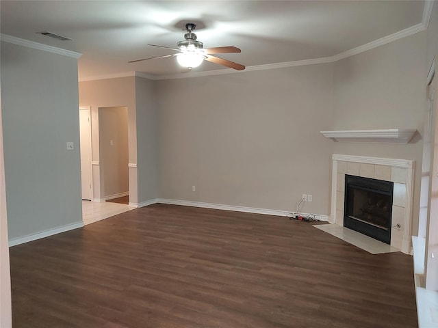 unfurnished living room with ceiling fan, a tiled fireplace, dark hardwood / wood-style flooring, and ornamental molding