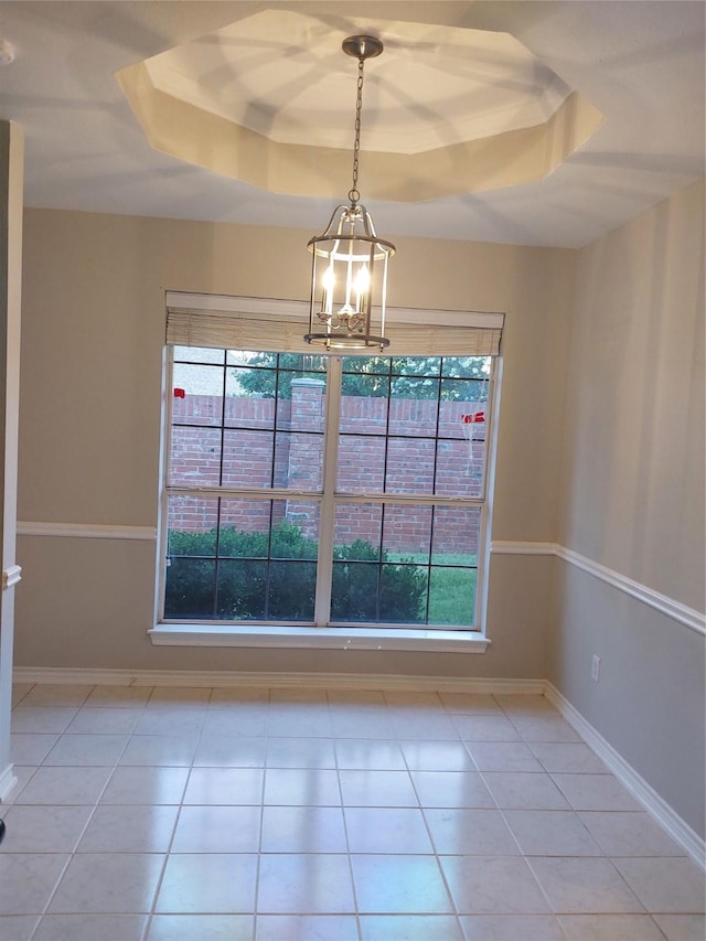 unfurnished dining area with light tile patterned floors, a notable chandelier, and a tray ceiling