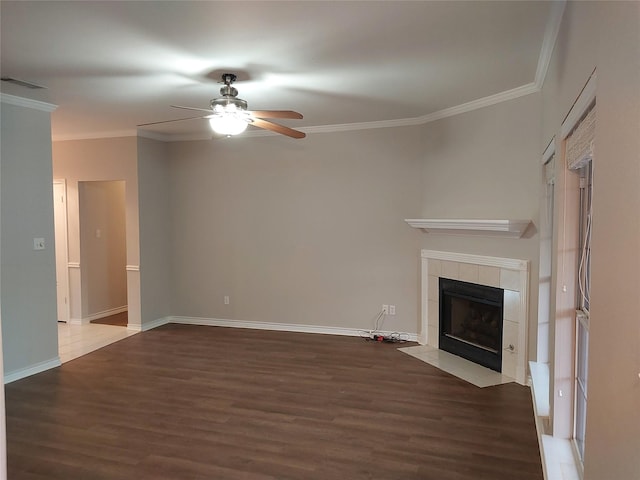 unfurnished living room featuring hardwood / wood-style flooring, ceiling fan, ornamental molding, and a tiled fireplace