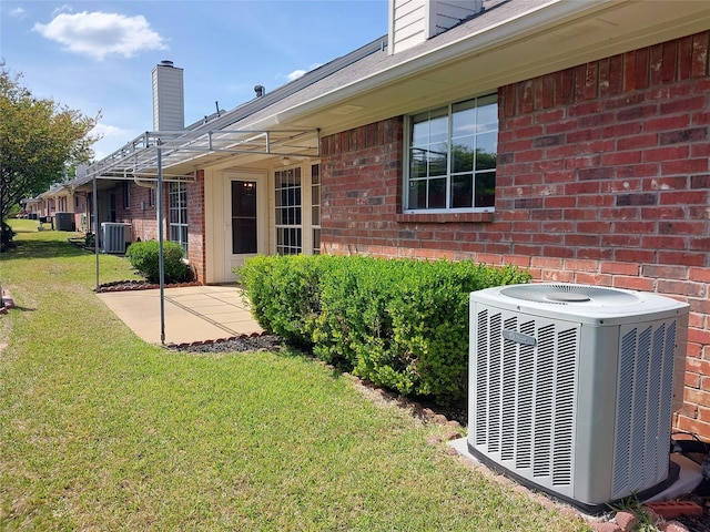 exterior space with a lawn, cooling unit, and a patio area